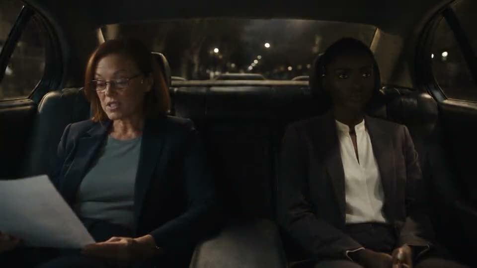 A person reviewing paperwork in the back seat of a car.